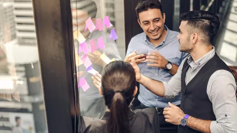 Image of 3 people with post-it notes on window
