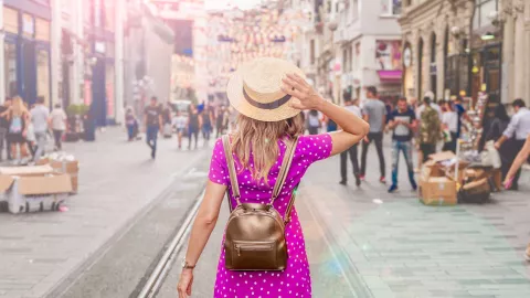 Woman with backpack hoding hat on head