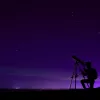 Image of person looking at the night sky through a telescope